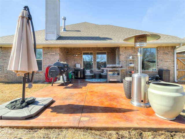 back of property with a patio, a shingled roof, and brick siding