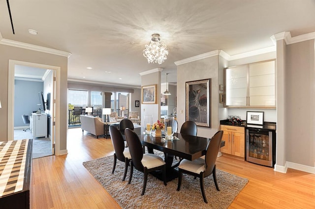 dining area featuring wine cooler, light wood-style flooring, baseboards, ornamental molding, and an inviting chandelier