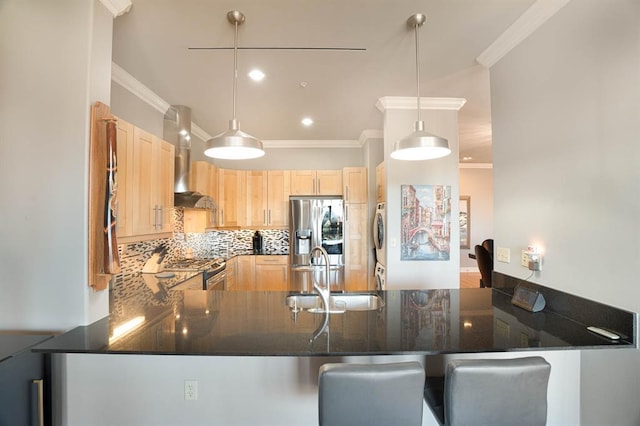 200 S Oklahoma Ave Unit 305, Oklahoma City, OK 73104 - kitchen with stainless steel appliances, stacked washer and clothes dryer, wall chimney range hood, light brown cabinets, and a peninsula