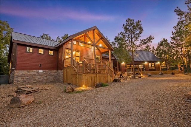 view of front facade featuring stone siding, central AC unit, and metal roof