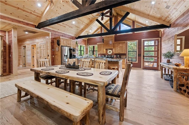 dining space with wooden ceiling, ceiling fan, light wood-type flooring, wood walls, and high vaulted ceiling