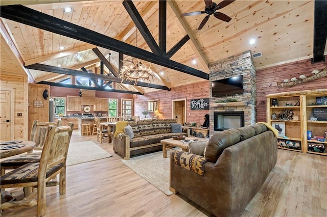 living area with light wood-type flooring, a stone fireplace, and wooden ceiling