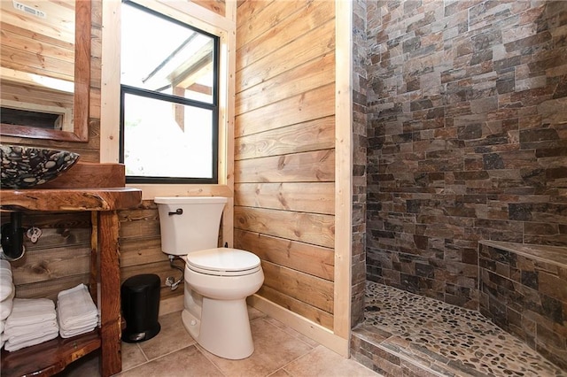 bathroom with toilet, wood walls, a shower stall, and tile patterned flooring