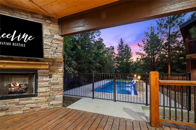 view of pool featuring a fenced in pool, an outdoor stone fireplace, and a patio area