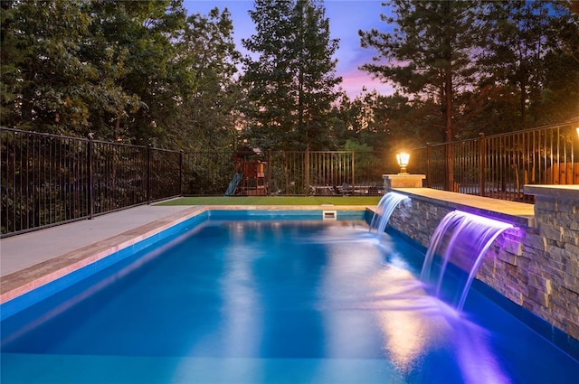 view of swimming pool featuring a playground, fence, and a fenced in pool