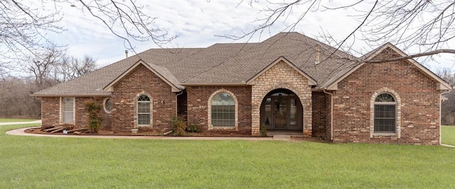 view of front facade featuring brick siding, a shingled roof, and a front lawn