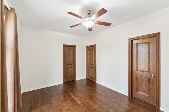 unfurnished room featuring a ceiling fan, baseboards, and dark wood-style flooring