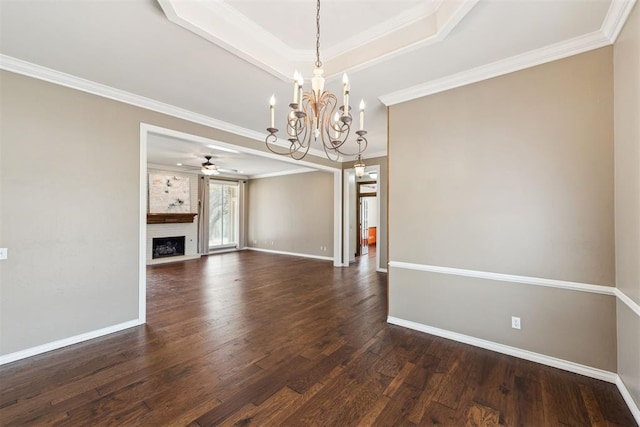 unfurnished living room with a raised ceiling, ornamental molding, a fireplace, baseboards, and dark wood-style flooring