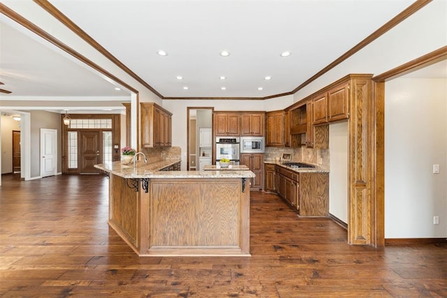 kitchen featuring light stone counters, appliances with stainless steel finishes, a peninsula, and dark wood finished floors