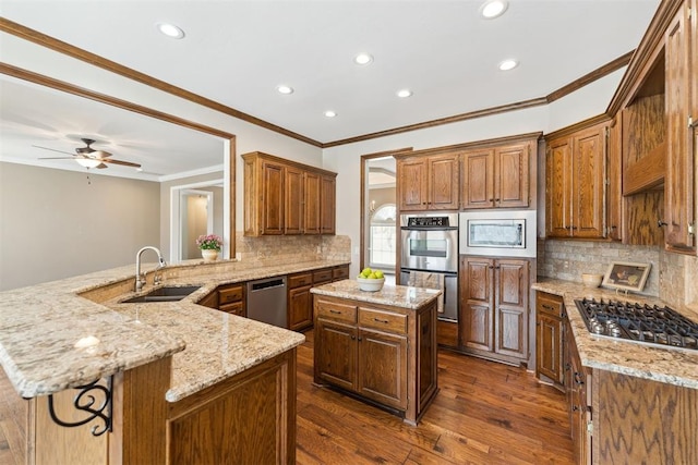 kitchen with light stone countertops, a peninsula, dark wood-style flooring, stainless steel appliances, and a sink