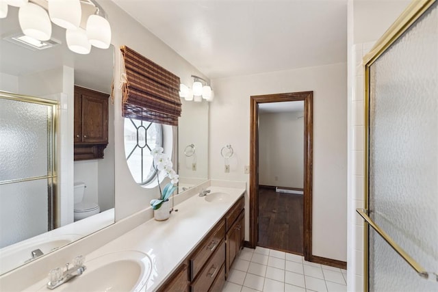 full bath with a sink, an enclosed shower, double vanity, and tile patterned floors