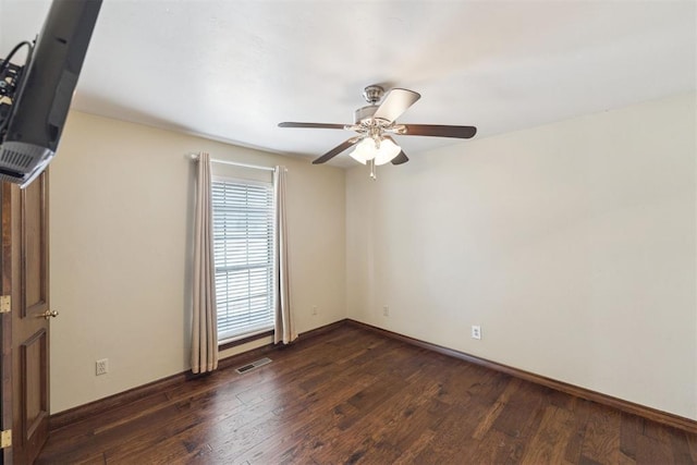 spare room with ceiling fan, visible vents, baseboards, and dark wood-style floors