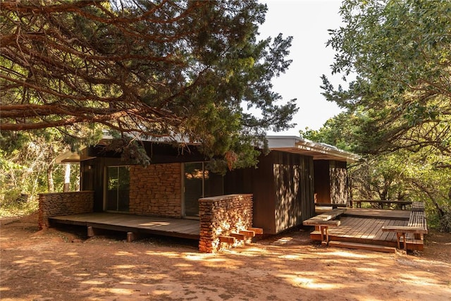 rear view of house featuring stone siding and a wooden deck