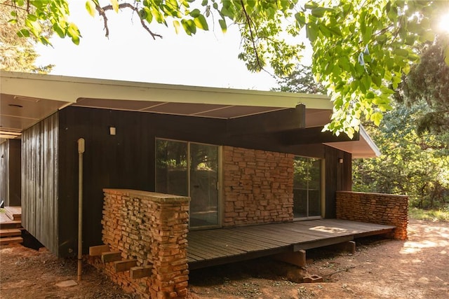 back of property with stone siding and a wooden deck