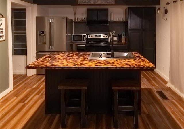 bar with appliances with stainless steel finishes, a sink, baseboards, and wood finished floors