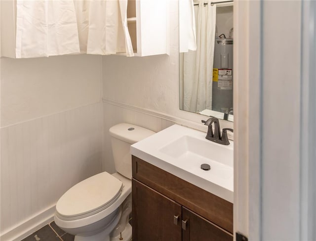 bathroom with wainscoting, toilet, tile patterned flooring, vanity, and water heater