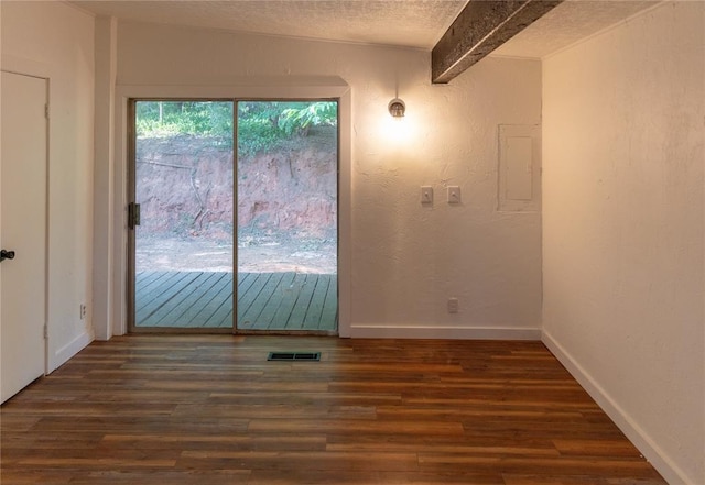 unfurnished room with visible vents, dark wood finished floors, a textured ceiling, and baseboards