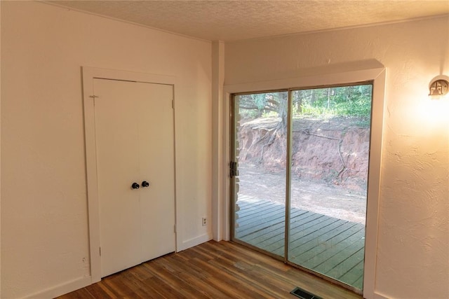 doorway to outside featuring a textured ceiling, wood finished floors, and a textured wall