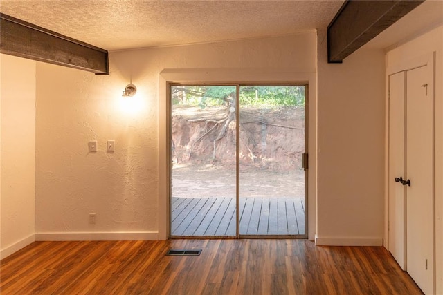 doorway to outside featuring a textured ceiling, a textured wall, dark wood-type flooring, and baseboards