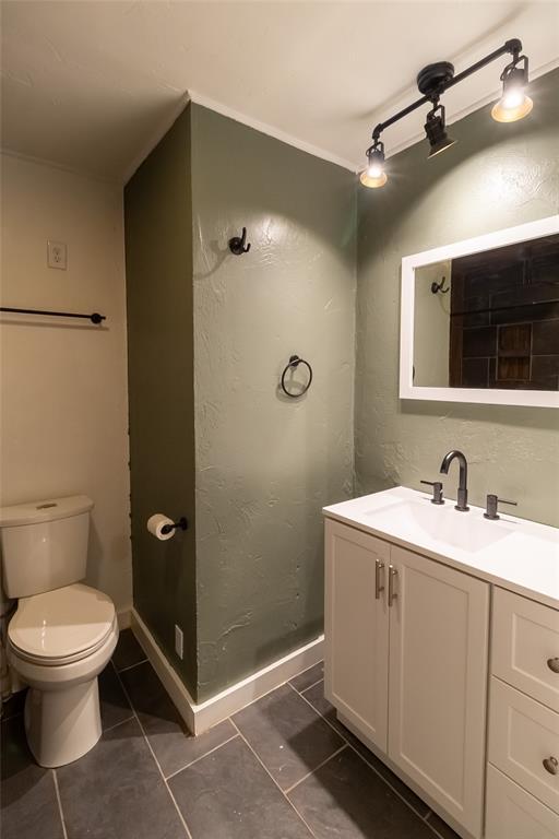 bathroom with toilet, tile patterned floors, baseboards, and vanity