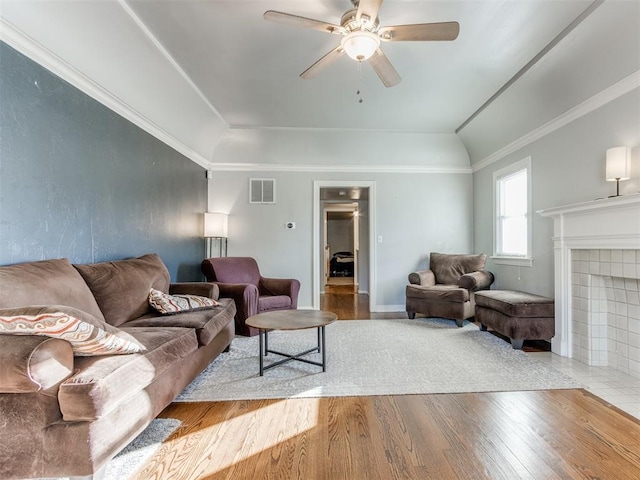 living room with visible vents, a tile fireplace, ceiling fan, wood finished floors, and vaulted ceiling