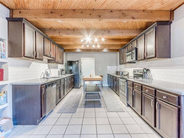 kitchen with dark brown cabinetry, light tile patterned floors, beamed ceiling, stainless steel appliances, and a sink