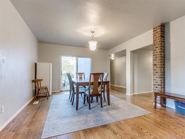 dining area with light wood-style flooring, baseboards, and a textured ceiling