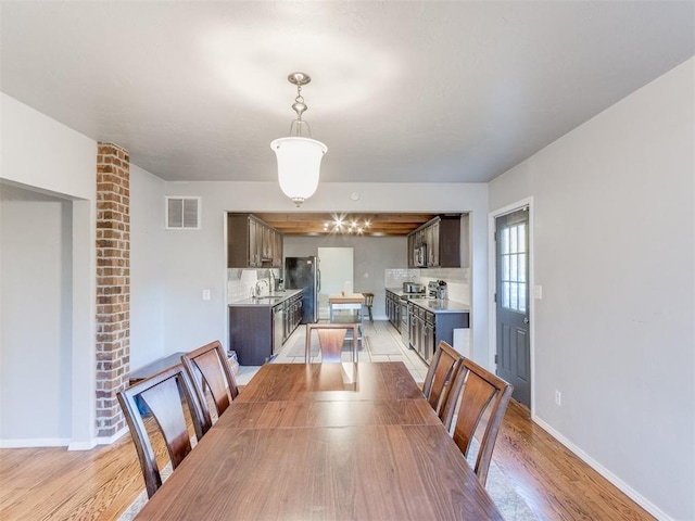 dining room featuring light wood finished floors, baseboards, and visible vents