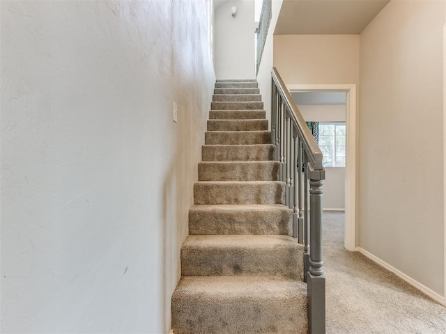 staircase featuring carpet floors and baseboards