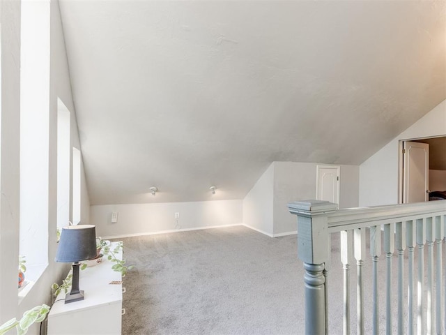 bonus room featuring baseboards, vaulted ceiling, and light colored carpet