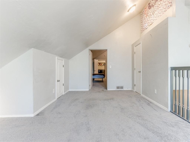 bonus room featuring lofted ceiling, baseboards, light carpet, and visible vents