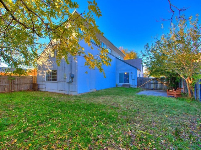 rear view of house featuring a patio, a lawn, and a fenced backyard