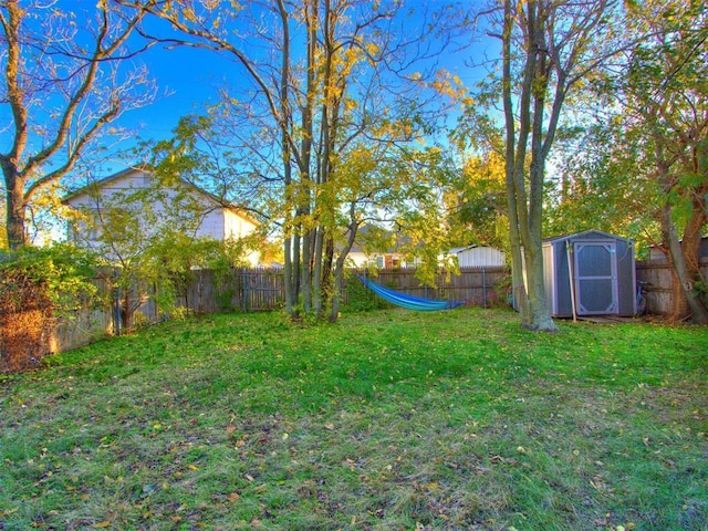 view of yard with a storage shed, a fenced backyard, and an outdoor structure