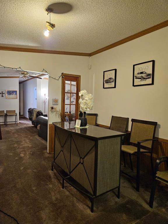 office space featuring ornamental molding, dark colored carpet, and a textured ceiling