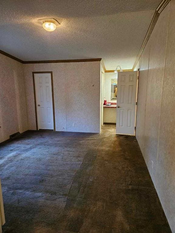 carpeted spare room featuring a textured ceiling and crown molding