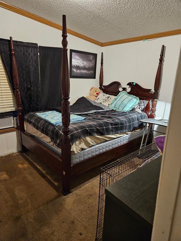 carpeted bedroom with ornamental molding and a textured ceiling