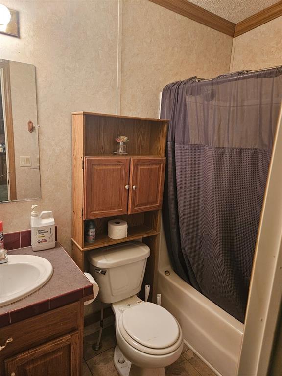 full bath with toilet, vanity, shower / bath combo with shower curtain, a textured ceiling, and crown molding