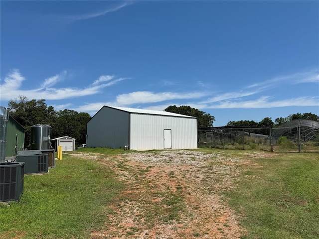 view of pole building with central AC, a yard, and fence