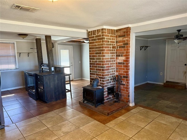 unfurnished living room featuring a textured ceiling, visible vents, a ceiling fan, a wood stove, and crown molding