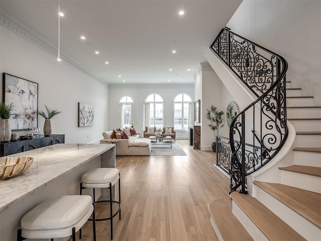 living room with stairway, recessed lighting, crown molding, and light wood-type flooring