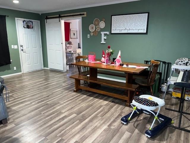 dining space featuring a barn door, recessed lighting, wood finished floors, and baseboards