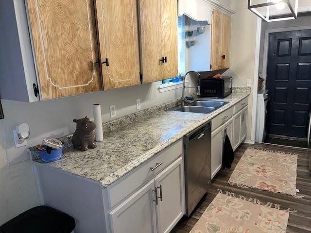 kitchen with dishwasher, dark wood-style floors, light stone countertops, and a sink