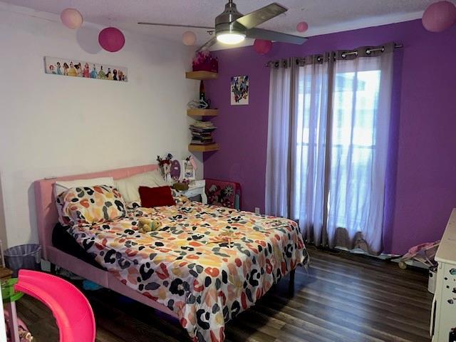 bedroom featuring multiple windows, wood finished floors, and a ceiling fan