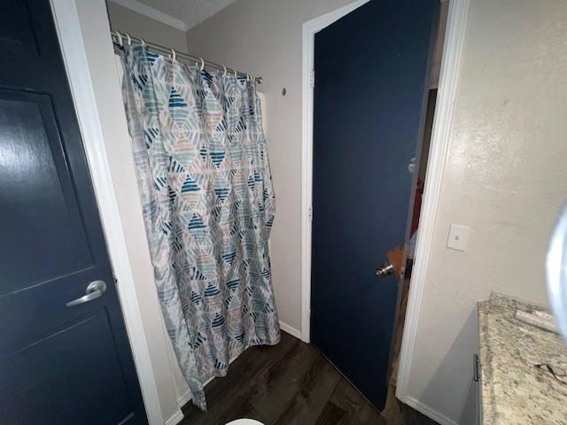 bathroom with curtained shower and wood finished floors