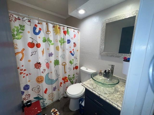 full bathroom with a shower with shower curtain, toilet, vanity, and a textured wall