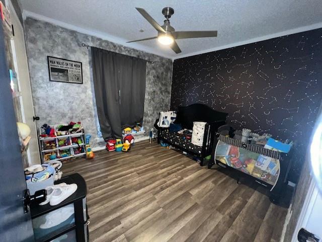 recreation room featuring a textured ceiling, a ceiling fan, and wood finished floors