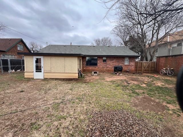 back of house featuring fence and brick siding