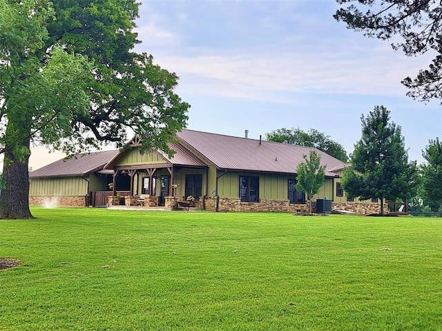 view of front facade with board and batten siding, metal roof, a front lawn, and central air condition unit