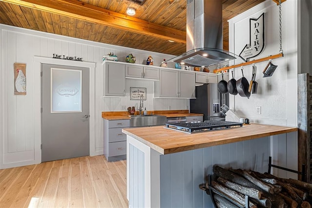 kitchen featuring stainless steel appliances, butcher block countertops, gray cabinets, and island exhaust hood