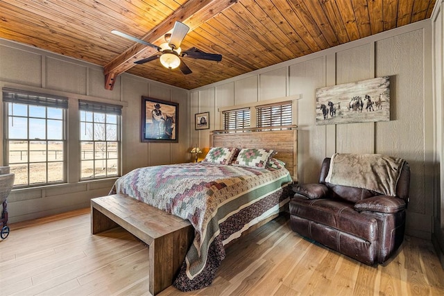 bedroom with wooden ceiling, wood finished floors, and a decorative wall